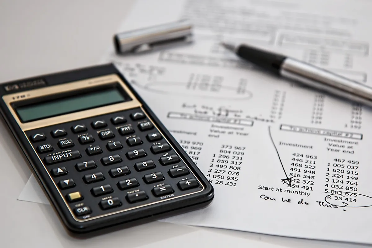 Calculator and pen resting on printed figures, used to plan an SEO budget