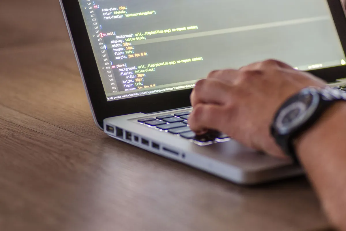 Close-up of hands typing code on a laptop, where a lot of website speed work happens